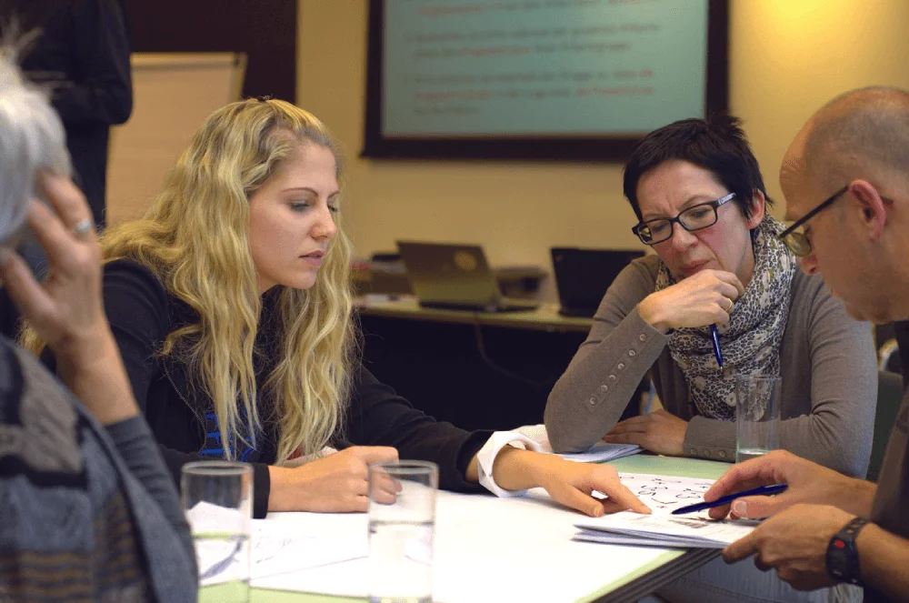 Staff working through a hands-on training session at a table, the kind of recurring live training ID Atlas converts into scalable on-demand modules for nonprofits.